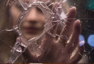 Pessoa refletindo diante de vidro fragmentado representando crenças limitantes sendo transformadas